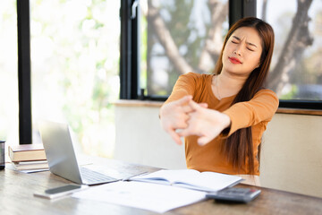 Obraz premium Office asian business woman stretching body for relaxing while working with laptop computer at her desk, office lifestyle, business situation.
