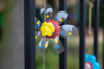 colorful flower ornaments made of recycled plastic bottles decorating a nursery school fence