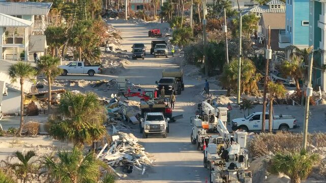 Hurricane Milton aftermath cleanup. Workers picking up piles of debris and sand on street side on Manasota Key in Florida.