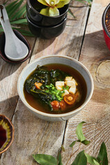 Miso soup with tofu and mushrooms, bright rustic lighting, overhead composition on wooden table