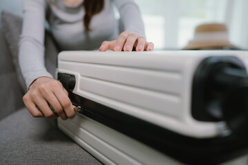 A person is neatly packing clothes into an open suitcase at home, preparing for a vacation or...