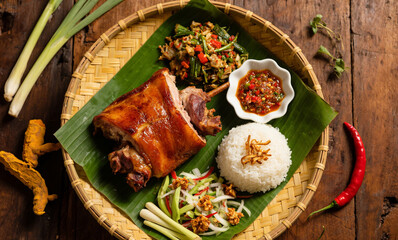 Top-Down View of Balinese Babi Guling with Lawar, Sambal Matah, and Rice on Banana Leaves over Rustic Tray with Herbs and Spices
