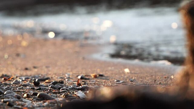 Beach peebles detail tracking shot, sea waves in the background