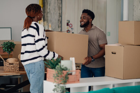 Colleagues moving cardboard boxes in new office space