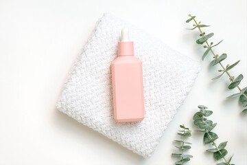 Pink cosmetic bottle on towel with green leaves for spa and relaxation