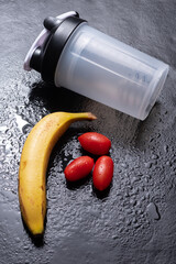 Healthy and natural snack combination with a shaker bottle, cherry tomatoes, and banana, ideal for clean eating, fitness routines, and nutritious energy on the go.