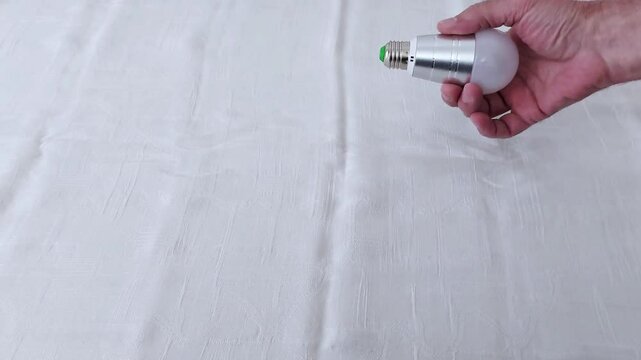 Soft light cradled in a human hand-an LED bulb against gentle folds of fabric. A study in warmth, texture, and the intimate feel of modern energy