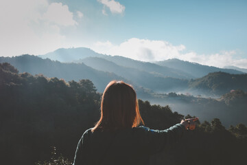 Woman hiking in forest on mountain with cliff