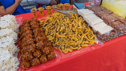 Variety of traditional sweets and snacks displayed on a market table with red cloth.
