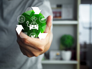 Green energy concept with electric car and recycling symbol held in hand, showing sustainable...