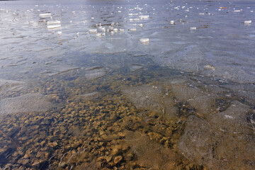 Ice fragments float on the surface of a frozen lake