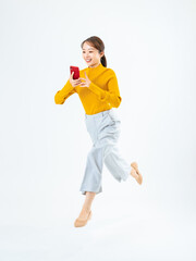 スマホを見ながらジャンプする女性の全身写真