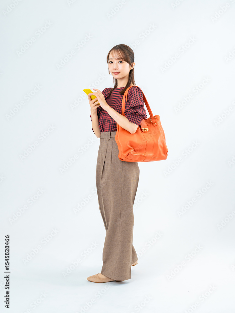 Aufkleber スマホを持って歩くカジュアルウェアの女性の全身写真