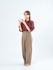 スマホを見るカジュアルウェアの女性の全身写真