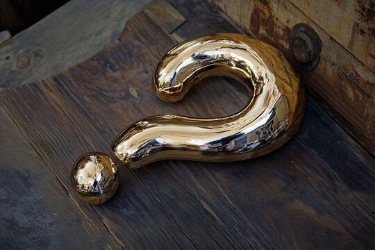 Golden question mark sculpture on dark wood background a mystery to solve - Powered by Adobe