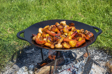 Champignons, grilled sausages and potatoes cooked on a cast iron saj. Picnic in the nature in...