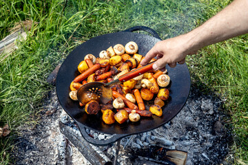Champignons, grilled sausages and potatoes cooked on a cast iron saj. Picnic in the nature in...
