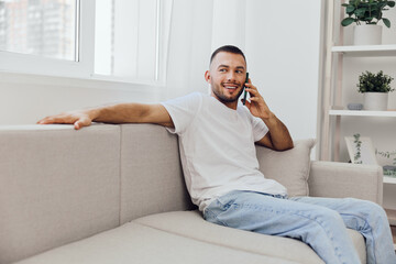 Smiling man talking on the phone with a relaxed posture, showcasing modern home decor, bright...