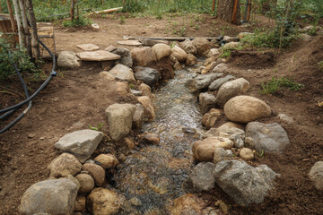 Low tech irrigation flows with rocks. System offers peaceful and natural vibe