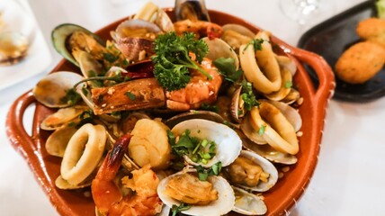 close up of Portuguese Arroz de Marisco, tomato brothy seafood rice  on a red plate taken in a restaurant in Macau