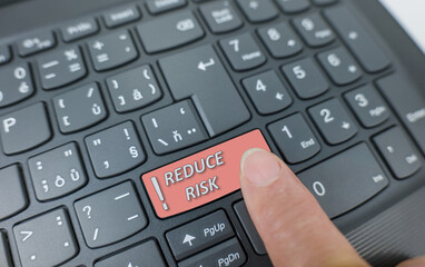 Reduce risk key on a gray keyboard. Finger pressing key