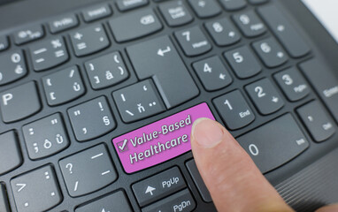 Value based healthcare key on a gray keyboard. Finger pressing key