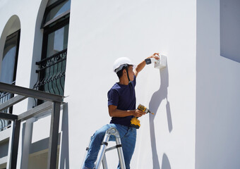 A technician installs a CCTV camera on the facade of a residential building