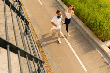 Joyful morning joggers enjoying the sunshine along a scenic pathway surrounded by green grass and...