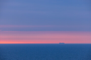 View from a cruise ship in the Norwegian Sea at sunset: the endless horizon glows with soft pink and blue tones. A tranquil ocean and sky background perfect for serene visuals.
