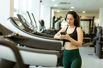 Woman enjoying music while using smartphone at gym during morning workout session