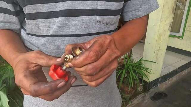 Auto mechanic checking car AC refrigerant pressure with gauge to detect leakage. Vehicle air conditioning maintenance and freon level inspection in a garage.