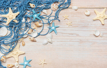 Fishing net, seashells, and starfishes creating a seaside border on wooden planks