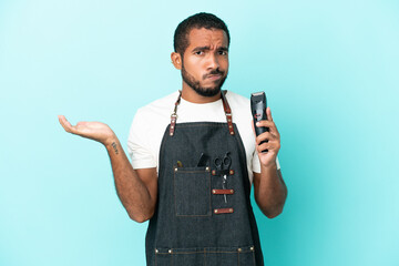 Young hairdresser latin man isolated on blue background having doubts while raising hands