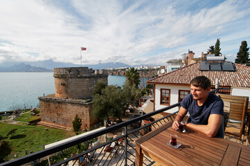 Scenic Mediterranean Cafe Terrace Overlooking Historical Tower and Serene Coastal Landscape
