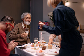 A group of people enjoying a festive dinner at home, sharing laughter and conversation in a warm...