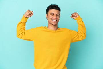 Young African American man isolated on blue background doing strong gesture