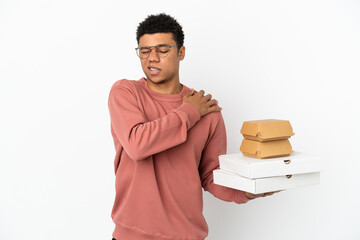 Young African American man holding a burger and pizzas isolated on white background suffering from...