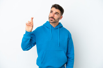 Young caucasian man isolated on white background with fingers crossing and wishing the best