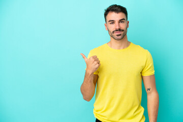 Fototapeta premium Young caucasian man isolated on blue background pointing to the side to present a product