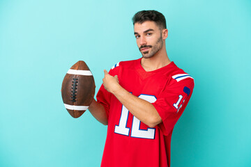 Young caucasian man playing rugby isolated on blue background pointing back