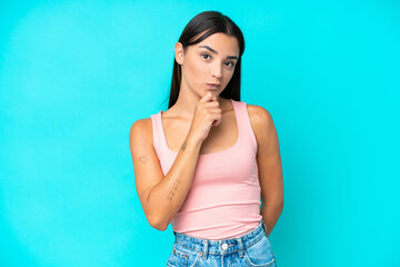 Young caucasian woman isolated on blue background and looking up