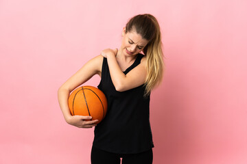 Young blonde woman playing basketball isolated on pink background suffering from pain in shoulder...