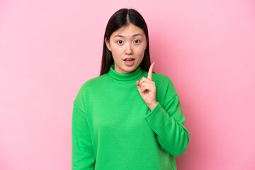 Young Chinese woman isolated on pink background intending to realizes the solution while lifting a...