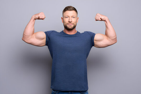 Confident young man flexing his arms and showing his muscular biceps. Fitness concept representing strength, masculinity, and a healthy lifestyle.