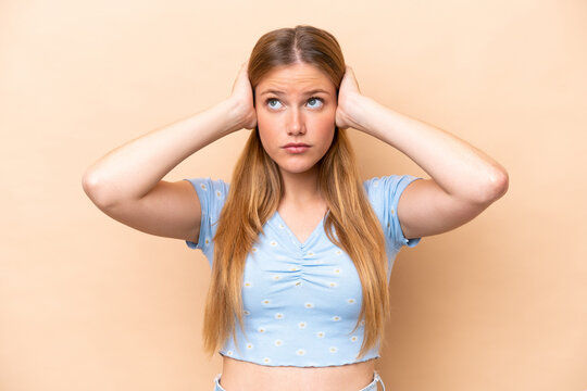 Young caucasian woman isolated on beige background frustrated and covering ears