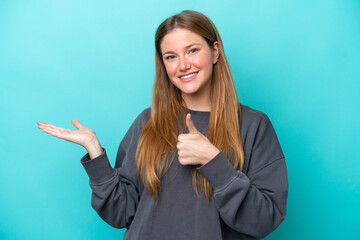 Young caucasian woman isolated on blue background holding copyspace imaginary on the palm to insert...
