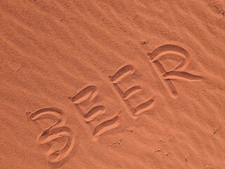 BEER writen in hot sand of desert WADI RUM in Jordan Arabia thirst on long distance Jordan trail