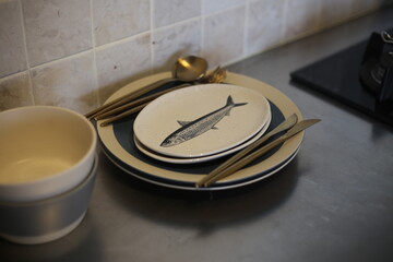 Fish-Illustrated Plate on Stack of Dishes with Cutlery