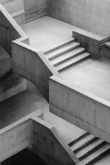 Black and white photo of a modern concrete stairwell with intersecting landings and geometric shapes, creating a sense of depth and architectural complexity
