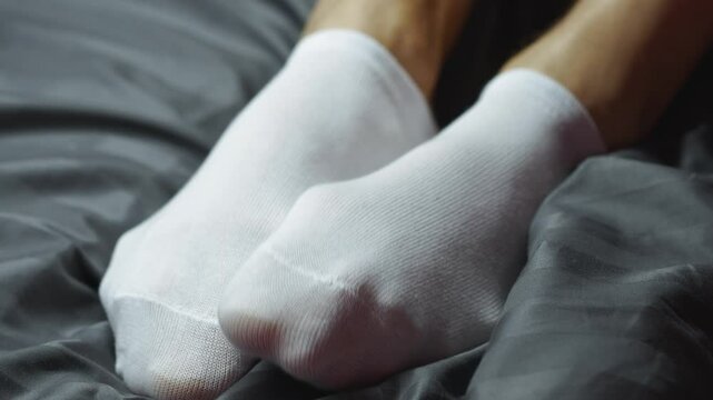 Man in white socks lying on bed after evening before sleep.
Close-up of male legs on sofa in white cotton sports socks.
Sports short socks